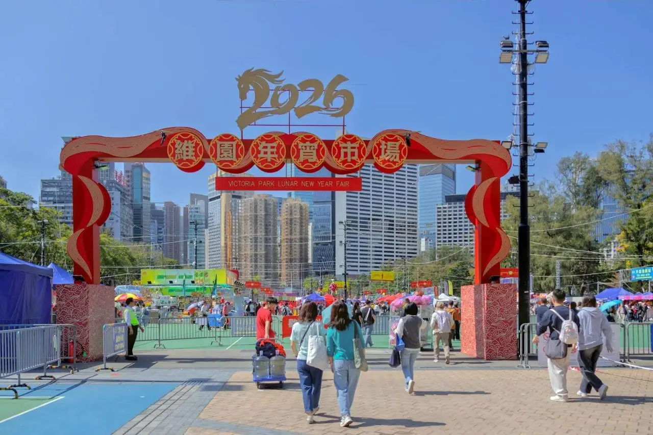 Crowds enjoying the vibrant 2026 Lunar New Year Fair at Victoria Park, Hong Kong under clear blue skies.