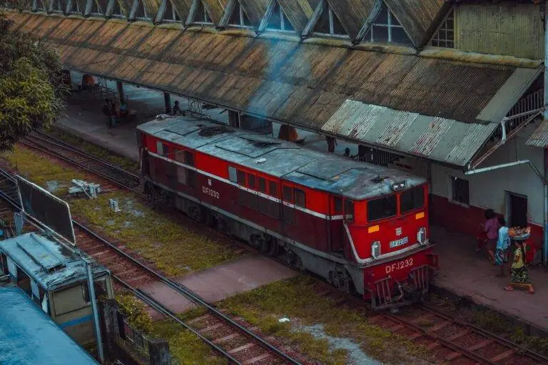 A red train captured at Yangon Railway Station with a classic, vintage vibe, showcasing local life.