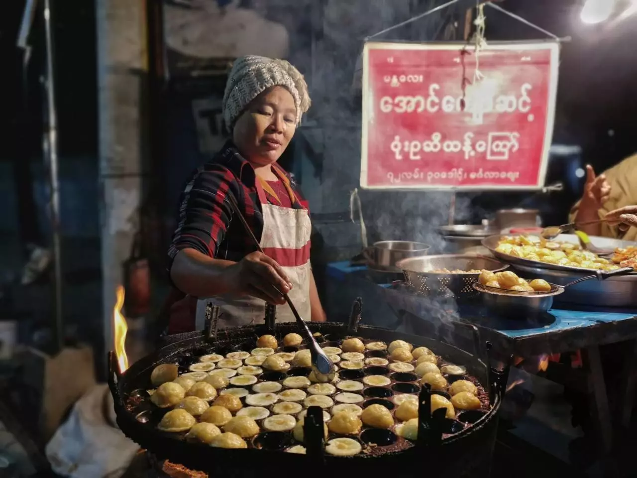 Street food vendor cooking traditional pastries at a market stall representing the popular Yangon street food scene and trends in 2026